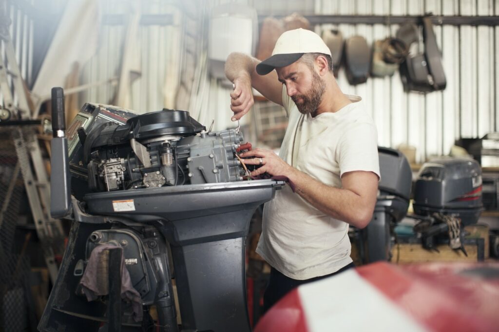 Man repairing outboard motor in boat repair workshop