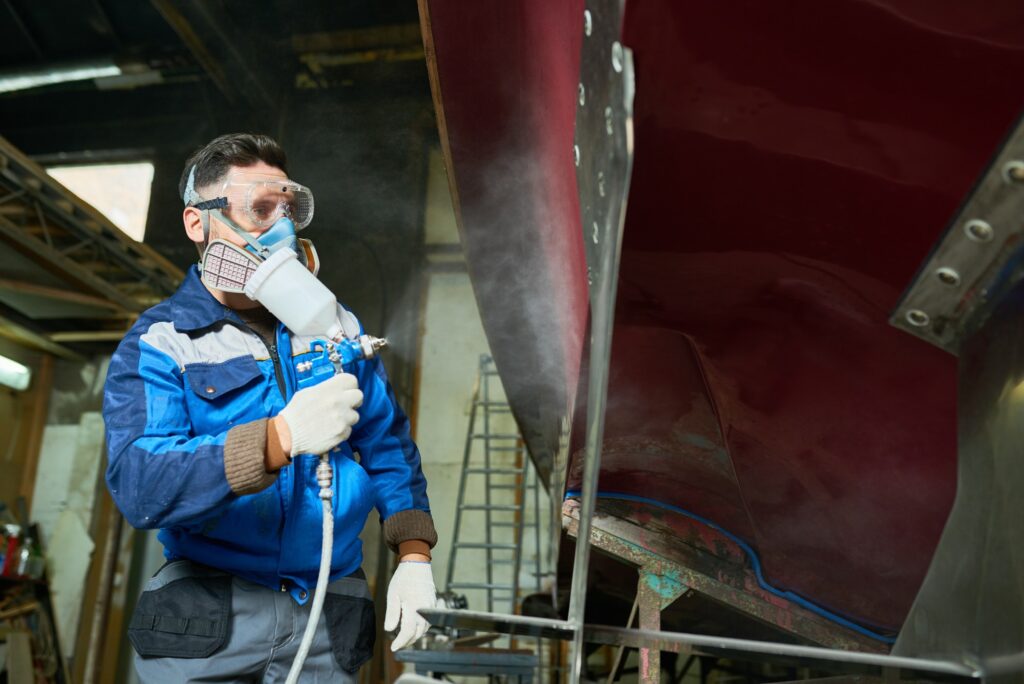 Worker Painting Boats in Yacht Workshop